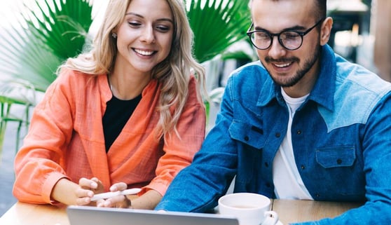 Male and female friends having fun together watching funny video on laptop.