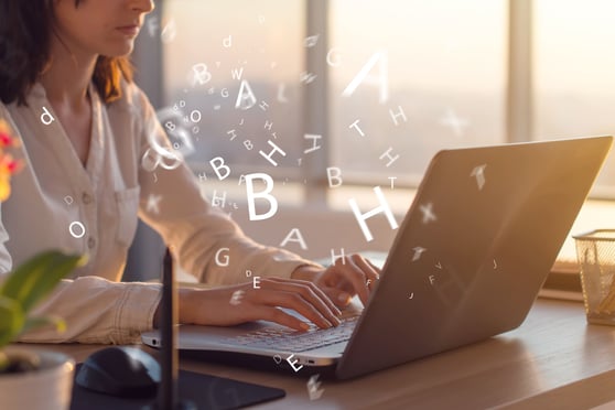 Person writing at a laptop, with letters floating around.