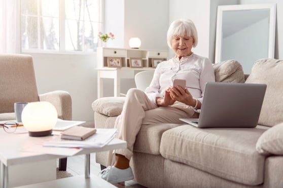 Elderly woman texting on her phone and smiling happily.