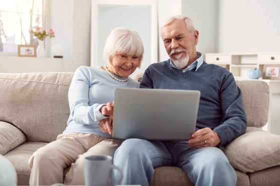 Husband and wife holding a laptop in their lap and surfing the Internet together