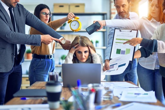 Busy woman in an office, with team members around her asking for help.