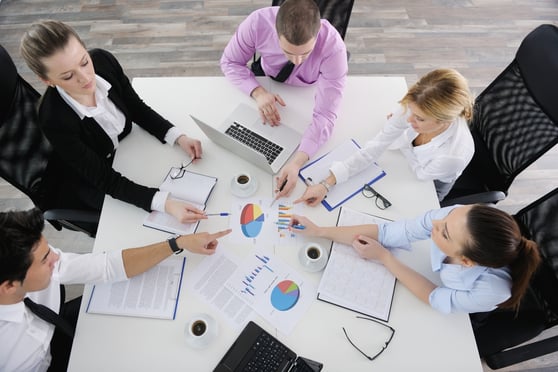 Group of young business people sitting in board room during meeting and discussing with paperwork